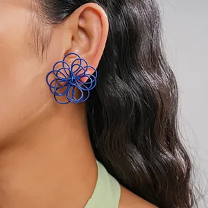 Primer plano detallado de pendientes de flores huecas azules envueltos en alambre en la oreja
