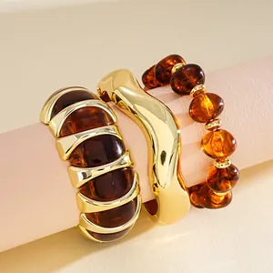 Detail view of retro amber acrylic and gold-toned bracelets on a pink display prop