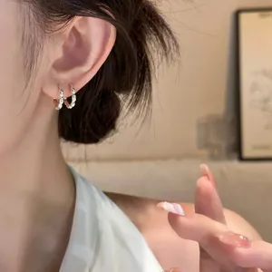 Close-up detail showing elegant silver scalloped hoop earrings worn on ear in warm light