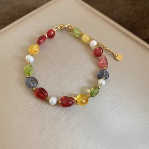 Detailed view of a colorful stone and pearl beaded bracelet with a gold chain finish.
