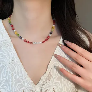 Beaded necklace featuring vibrant multi-colored stones and small white pearls on a model.