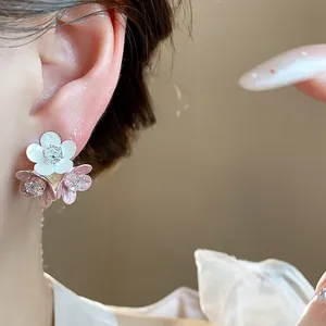Detailed macro view of elegant pink and white enamel flower stud earrings with shiny zircons