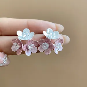 Close-up of elegant flower stud earrings with zircon centers and pink enamel petals