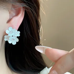 Macro view of elegant white enamel flower stud earrings featuring sparkling zircon centers
