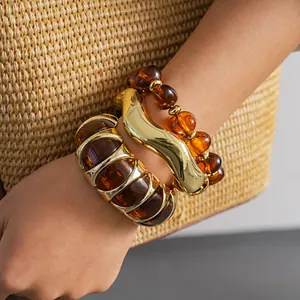Macro detail of vintage amber acrylic beaded bracelet and wavy gold bangle jewelry set