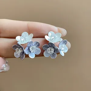 Close-up of elegant flower stud earrings with shimmering zircons and oil-drop petals