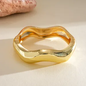 Elegant high-shine gold wavy metal bangle with organic design shown in macro detail