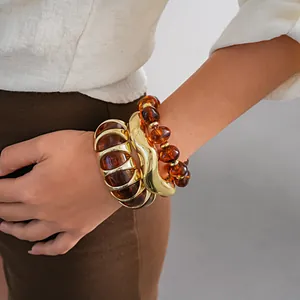 Detailed view of retro amber acrylic beaded bracelets and gold bangles set