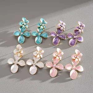Vue détaillée de boucles d'oreilles fleurs en émail coloré avec cœurs en strass divers.
