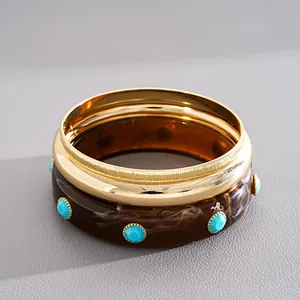 Close-up of retro three-piece resin and gold-tone metal bangle set with marbled pattern
