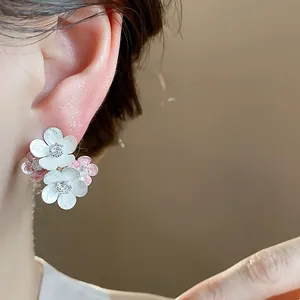Detailed view of elegant pink and white enamel flower stud earrings with zircon centers