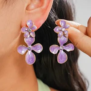 Détail de boucles d'oreilles fleurs violettes avec des strass étincelants de luxe.