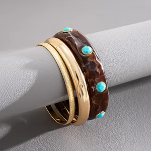 Detailed view of a three-piece retro resin and gold bracelet set on grey stand