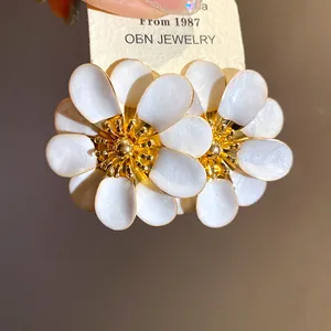 Dettaglio macro di eleganti orecchini a lobo a fiore bianco con splendidi accenti dorati
