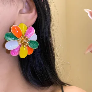 Vista dettagliata di orecchini a lobo a fiore in smalto multicolore su una modella
