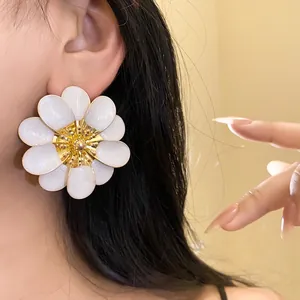 Dettaglio di orecchini a lobo a forma di fiore in smalto bianco e oro