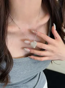 Detailed view of an elegant silver beaded heart pendant necklace on a female model