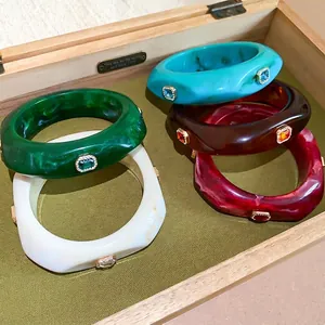 Chunky colorful resin bangle set with sparkling gemstone inlays in a jewelry box
