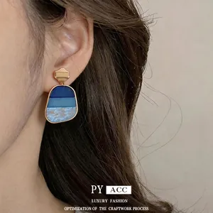 Eleganti orecchini a pendente con gradiente blu in una montatura dorata di lusso.