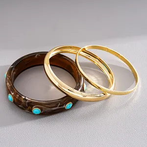Detail view of retro three-piece set with brown marbled resin and gold bangles.