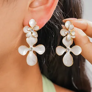 Vue détaillée de boucles d'oreilles fleurs blanches avec un strass étincelant