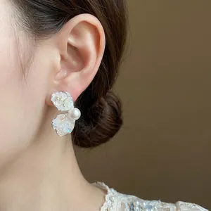 Elegant silver needle stud earrings featuring crushed stone petals and a pearl accent