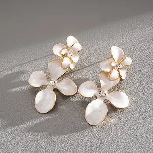 Vue détaillée des boucles d'oreilles en émail blanc avec fleurs et strass brillants