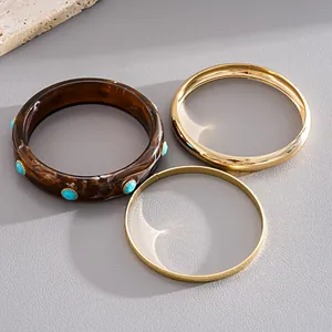 Set of three vintage bangles featuring a swirled resin cuff and two gold-toned metal rings
