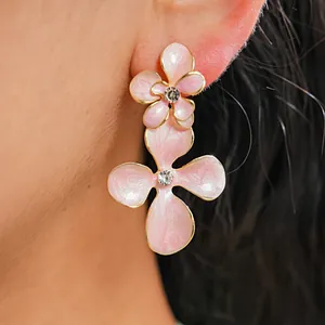 Détail de boucles d'oreilles en émail rose en forme de fleur avec strass brillants