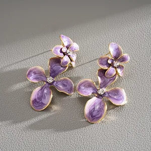 Gros plan détaillé de boucles d'oreilles fleurs en émail violet avec centres en strass