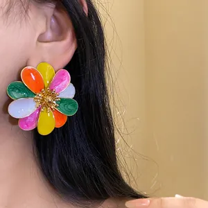Dettaglio ravvicinato di un vivace orecchino a fiore in smalto colorato su una modella