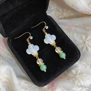 Primo piano di orecchini stile cinese con petali di trifoglio bianco e perle verdi