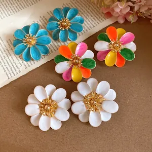 Dettaglio ravvicinato di orecchini a fiore in smalto colorato blu, bianco e multicolore