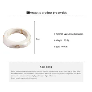 Detailed specs of white marbled resin bangle with rhinestone accents