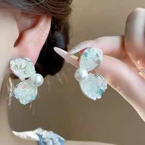 Detail of elegant crushed stone petal earrings with lustrous white pearl accents