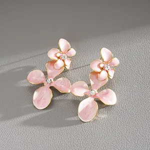 Détail de boucles d'oreilles fleurs en émail rose avec centre en strass brillant