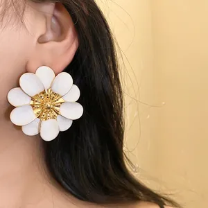 Primo piano dettagliato di un grande orecchino a fiore in smalto bianco sull'orecchio