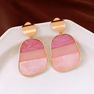 Dettaglio di orecchini in resina tricolore rosa con trama marmorea e perni dorati