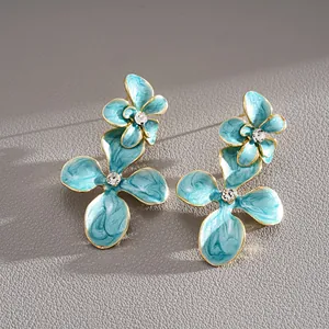 Détail macro des boucles d'oreilles fleurs en émail bleu avec de brillants strass