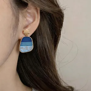 Primo piano di orecchini a pendente vintage in resina marmorizzata blu su modella