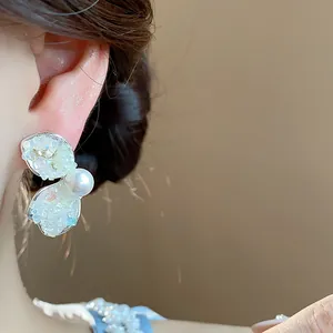 Detailed macro shot of French style pearl earrings with shimmering crushed stone petals.