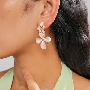 Vue détaillée de boucles d'oreilles fleurs en émail rose avec centre en strass.