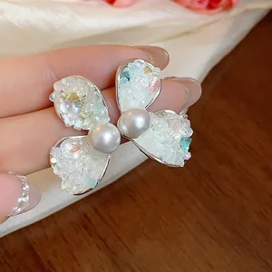 Detailed close-up view of French-style pearl stud earrings with crushed stone butterfly wings