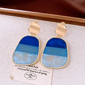 Vista dettagliata di orecchini a pendente vintage geometrici in resina blu sfumata.