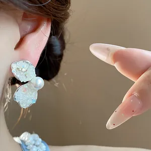 Detailed macro view showing the crushed stone wing stud earring with pearl on ear