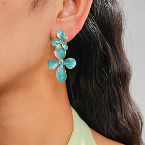 Gros plan de boucles d'oreilles fleurs en émail sarcelle avec strass brillants