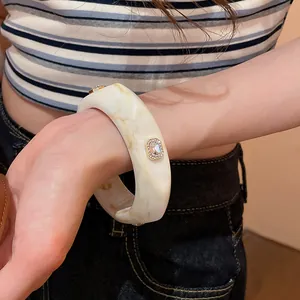 Close-up of a chunky marble-pattern resin bangle with sparkling rhinestone details