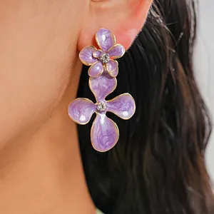 Vue macro détaillée de boucles d'oreilles fleur en émail violet avec centre en strass