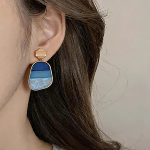 Dettaglio ravvicinato di orecchini vintage in resina blu indossati da una modella elegante