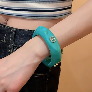 Close-up of a chunky turquoise resin bangle with an inlaid green gemstone detail